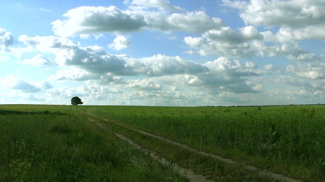 Clouds over the rural road  in field. Timelapse