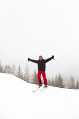 Ski man with long blonde hair and sunglasses standing in snow.