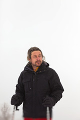 Ski man with long blonde hair and beard standing in snow.