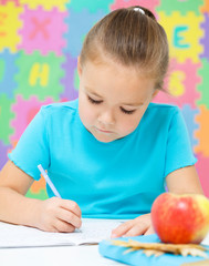 Little girl is writing using a pen