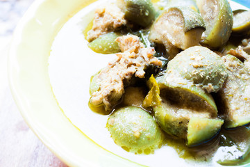 A bowl of spicy green curry with chicken and eggplant