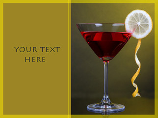 Red cocktail in martini glass on dark yellow background