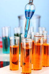 Laboratory pipette with drop of color liquid over glass test