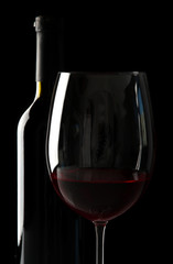 Glass of wine with bottle on black background