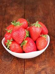 Fresh strawberry in bowl on wooden background