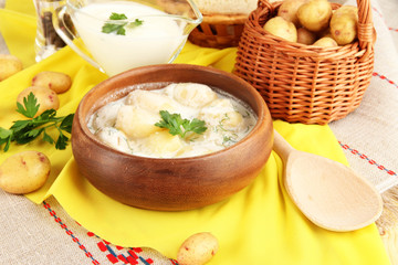 Tender young potatoes with sour cream and herbs in wooden bowl
