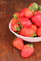 Fresh strawberry in bowl on wooden background