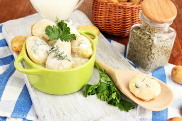 Tender young potatoes with sour cream and herbs in pan