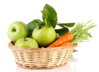 Juicy green apples and carrots with leaves in basket, isolated