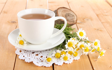 Cup of chamomile tea and chamomile on wooden table