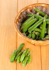 Green peas in basket on wooden table