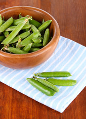 Green peas in wooden bowl on napkin on table