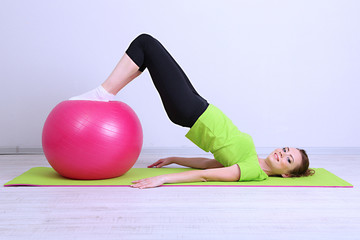 Portrait of beautiful young woman exercises with gym ball