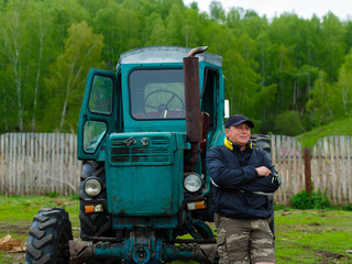 Portrait farmer standing in front of his old tractor