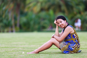 Asian woman sit and smile in park