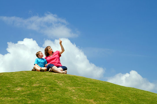 Mother And Son Watching Clouds From Grassy Hill