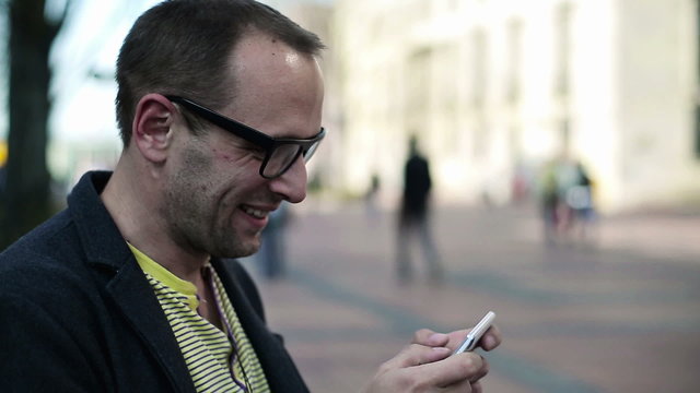 Young happy man using smartphone in the city
