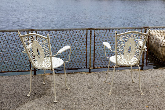 Two white chairs overlooking the water