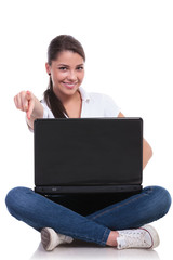 casual woman sits with laptop & points