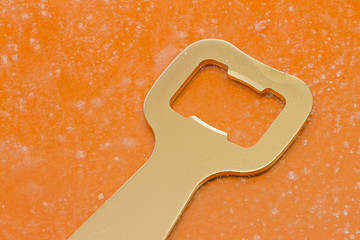 Golden bottle opener on orange background
