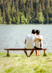 Fototapeta premium Young lovers sitting on wooden bench