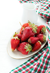 Strawberries on plate and milk over light background