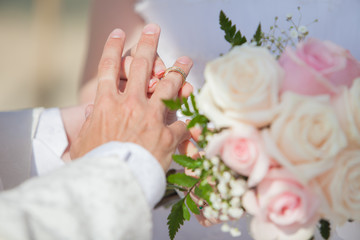 Obraz na płótnie Canvas Bride putting a wedding ring on groom's finger