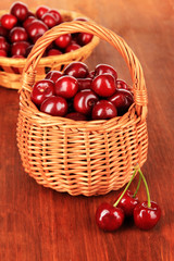 Cherry berries in wicker baskets on wooden table close-up