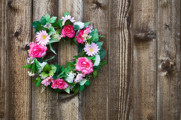Pink flower wreath hanging on rustic wooden fence