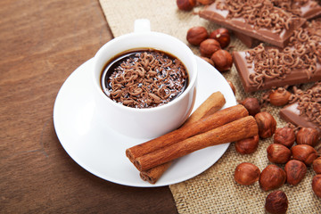 A cup of coffee with cinnamon sticks in a saucer, chocolate and