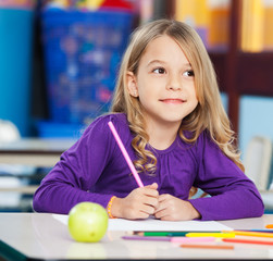 Thoughtful Girl With Sketch Pen And Paper In Classroom