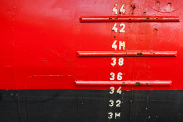 Red ship hull with waterline and draft scale measure