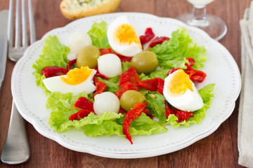 salad with egg and olive on the white plate