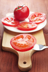 Slices tomato on a fork and in a plate