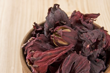 Dry hibiscus tea flowers in wooden bowl close up