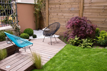 Terrasse et et petit jardin moderne, coin zen avec du gravier blanc et un érable japonais, fauteuils et pelouse, palissade en bois