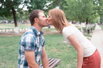 young couple kissing on bench