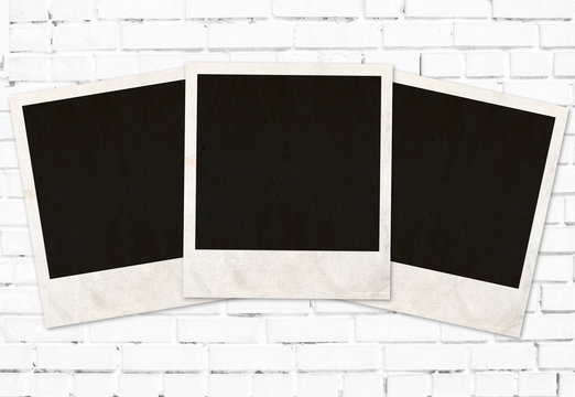 three photo frames against white brick wall