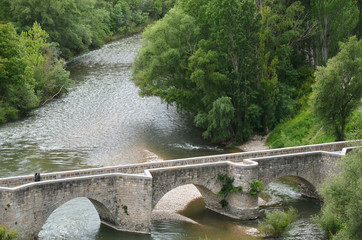 puente medieval de piedra sobre el río y  arboles