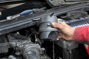 Mechanic replacing fuel filter at car diesel engine