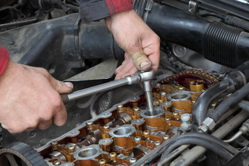 Mechanic fix car engine with ratchet, visible camshaft