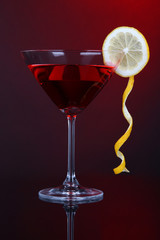 Red cocktail in martini glass on dark red background