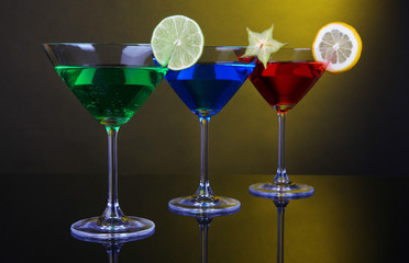Alcoholic cocktails in martini glasses on dark yellow