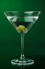 Martini glass with olives on dark green background