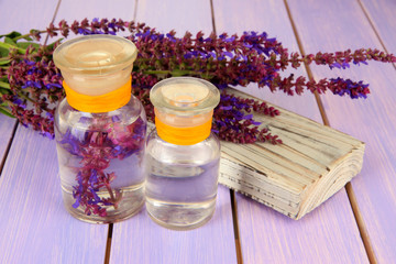 Fototapeta na wymiar Medicine bottles with salvia flowers on purple wooden