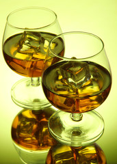 Brandy glasses with ice on green background