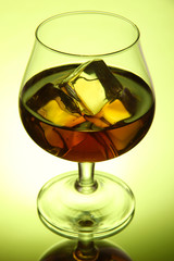 Brandy glass with ice on green background