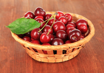Fototapeta na wymiar Cherry berries in wicker basket on wooden table close-up