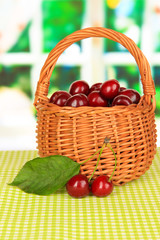 Cherry berries in wicker basket on table in room