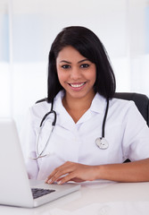 Happy Female Doctor Using Laptop